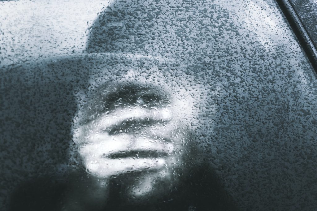 Person closing face by hand in glass with glaze ice