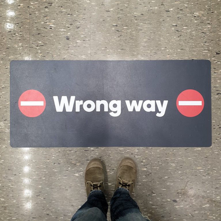 Lower section of person standing directly above sign ,wrong way